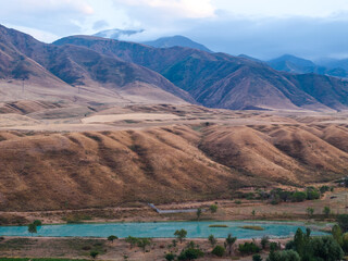 Landscape from a drone: yellow mountains and a lake in the valley. Cloudy autumn weather.