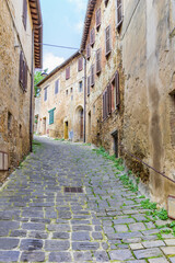 Cobblestoned street with old houses in Montalcino, Italy