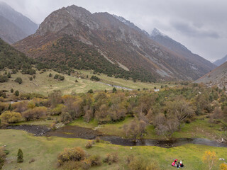 Summer landscape from a drone: mountains, valley with a stream and trees in the evening in cloudy...
