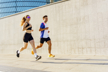 Fototapeta premium Two runners exercising on a sunny day along a modern urban pathway