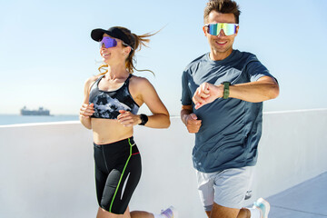 Fitness enthusiasts run along a coastal pathway with city views during a sunny morning