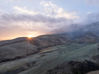 Mountains at sunset in the sun, view from a drone. Beautiful clouds on the sky.