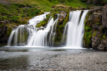Obraz premium Kirkjufellsfoss waterfall plunging into a serene icelandic landscape