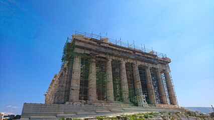 Athens, Greece - 29.3.2018: Side view of Parthenon with scaffoldings under repairs and maintenance under a clear blue sky in the summer before the pandemic