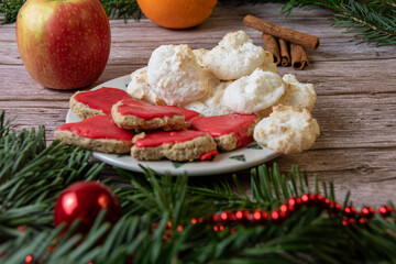 Ein Teller mit Ausstechplätzchen in Herzform mit rotem Guss und Makronen ,auf dem tisch liegt im Vorder- und Hintergrund sind Weihnachtlich ausgeschmückt