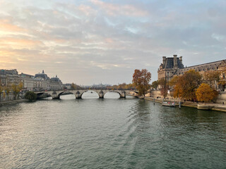 Obraz premium Picturesque view of a Parisian bridge with the Pavillon de Flore, the Seine’s quays, and a vibrant sky at sunset
