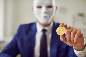 Bitcoin in hand of masked secret man, cryptocurrency scam, financial criminal of digital wallet....