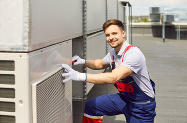 Portrait of a smiling man engineer conducting an inspection and maintenance of an HVAC system on a...