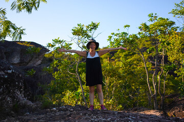 woman standing on a rock with trees behind