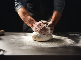 Close-up of hands kneading dough on a dark countertop, flour dusting the surface.  The baker's hands are strong and focused on the process.