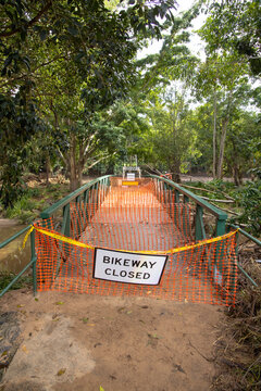 A safety barrier blocks a bridge crossing along a suburban bikeway after a flood event