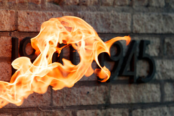 Flames engulfing a brick wall, likely commemorating 1945.  A memorial or remembrance.