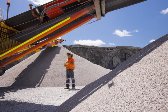 Man standing in between piles of aggregates near the crusher.