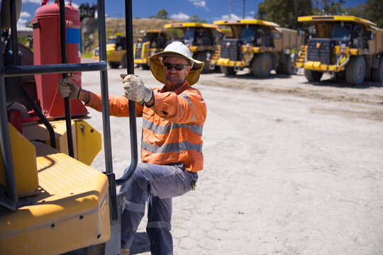 Mining operator man holding on the handrails while climbing up the dump truck