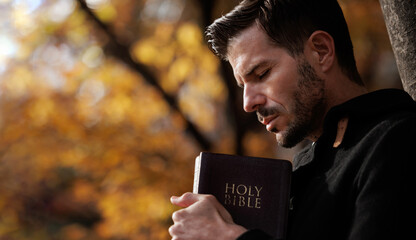 Christian tightly hug and pray with holy bible in autumn with Holy light shining. Pray to God to...
