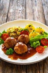 Seared pork meatballs with sauce, boiled potatoes and cabbage salad on wooden table	