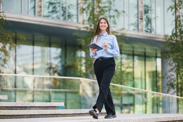 Young professional woman walks confidently outside modern glass building during the day