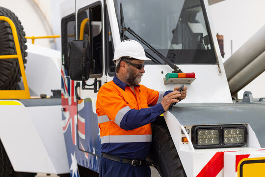 man working on the digital tablet beside oversize crane truck on industrial site