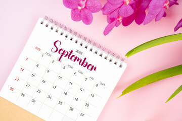 Desk calendar for September 2025 with blooming pink orchid.