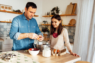 An attractive man and his sweet daughter cook together in the kitchen. A young dad teaches a...
