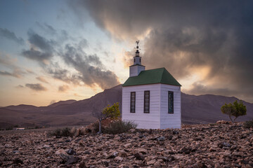 small cute white wooden chapel in a barren volcanic landscape. Sunrise, landscape shot of Ermita...