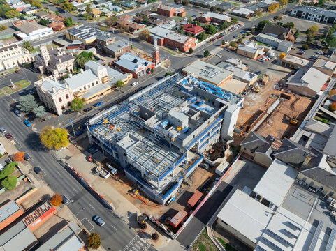 Aerial view of multi level construction site alongside existing city buildings