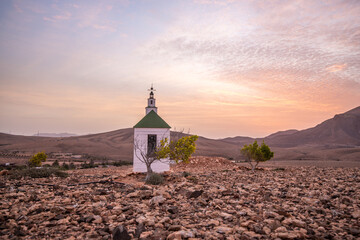 small cute white wooden chapel in a barren volcanic landscape. Sunrise, landscape shot of Ermita...