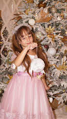 beautiful little girl looks like queen near the christmas tree