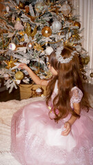 beautiful little girl looks like queen near the christmas tree