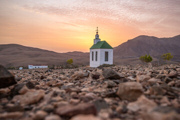 small cute white wooden chapel in a barren volcanic landscape. Sunrise, landscape shot of Ermita...