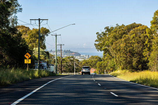 recommended speed of 75 km/h on bend in coastal Newcastle road with single car traveling on left