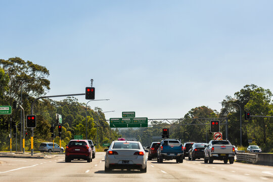 Traffic with break lights on approaching intersection with sign over road