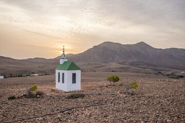 small cute white wooden chapel in a barren volcanic landscape. Sunset, landscape shot of the Ermita...