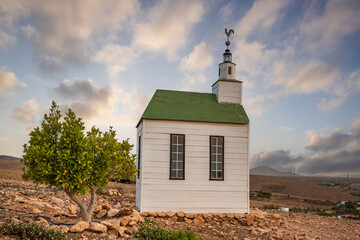 small cute white wooden chapel in a barren volcanic landscape. Sunset, landscape shot of the Ermita...