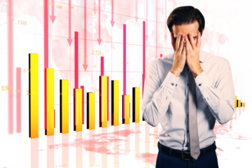 Businessman in formal attire covering face with hands, vivid financial charts showing downward trends, red arrows, and bar graphs behind