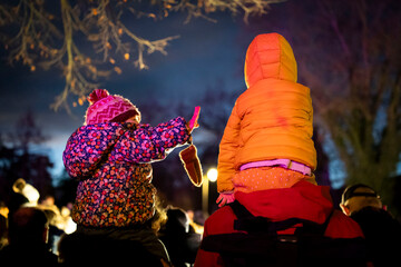 Deux enfants sur les épaules de leurs parents observent un spectacle