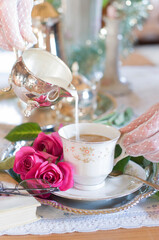 Tea break in English style, female hands in white lace gloves pouring cream into a porcelain cup, antique still life, coffee service, shallow depth of field, light and air, Christmas mood,
