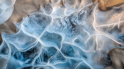 Obraz premium Thin sheets of ice partially buried in desert sands, with intricate patterns visible through translucent frozen layers