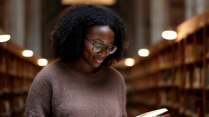 A Black woman reads peacefully in a library filled with wooden shelves and countless books