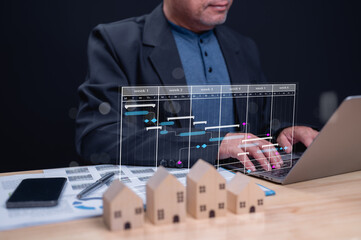 Professional managing real estate project with digital Gantt chart on laptop, highlighting tasks...