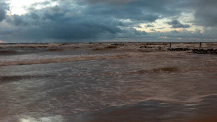 dramatic storm in the Baltic Sea, large waves crashing against the shore, blurred, unclear contours, rocky shore of Vidzeme
