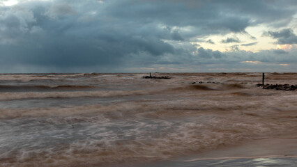 dramatic storm in the Baltic Sea, large waves crashing against the shore, blurred, unclear contours, rocky shore of Vidzeme