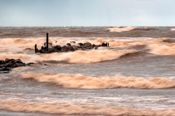 dramatic storm in the Baltic Sea, large waves crashing against the stone pier, blurred, unclear...