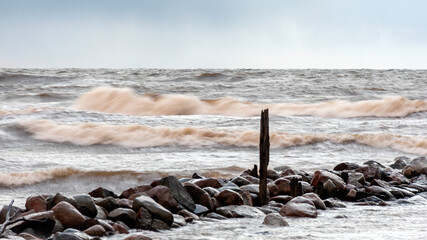 dramatic storm in the Baltic Sea, large waves crashing against the stone pier, blurred, unclear...