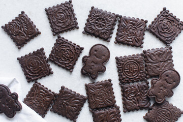 Overhead view of stamped chocolate cookies on a parchment lined baking tray, top view of embossed chocolate sugar cookies on a white background