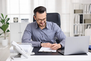 Naklejka premium Handsome banker signing document at table in office
