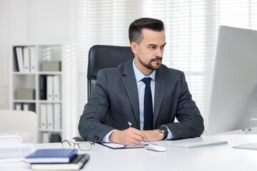 Obraz premium Handsome banker working with computer at table in office