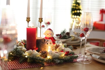 Christmas place setting with festive decor on wooden table in room