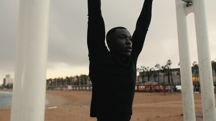 Close-up of strong man's hands, athlete doing pull-ups in outdoor gym