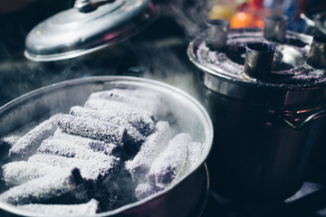 Casserole pot of grated coconut coated Puto bumbong, a popular Filipino dessert of steamed purple rice cakes in sticky logs sold during Christmas season and made from pirurutong -  purple sticky rice.